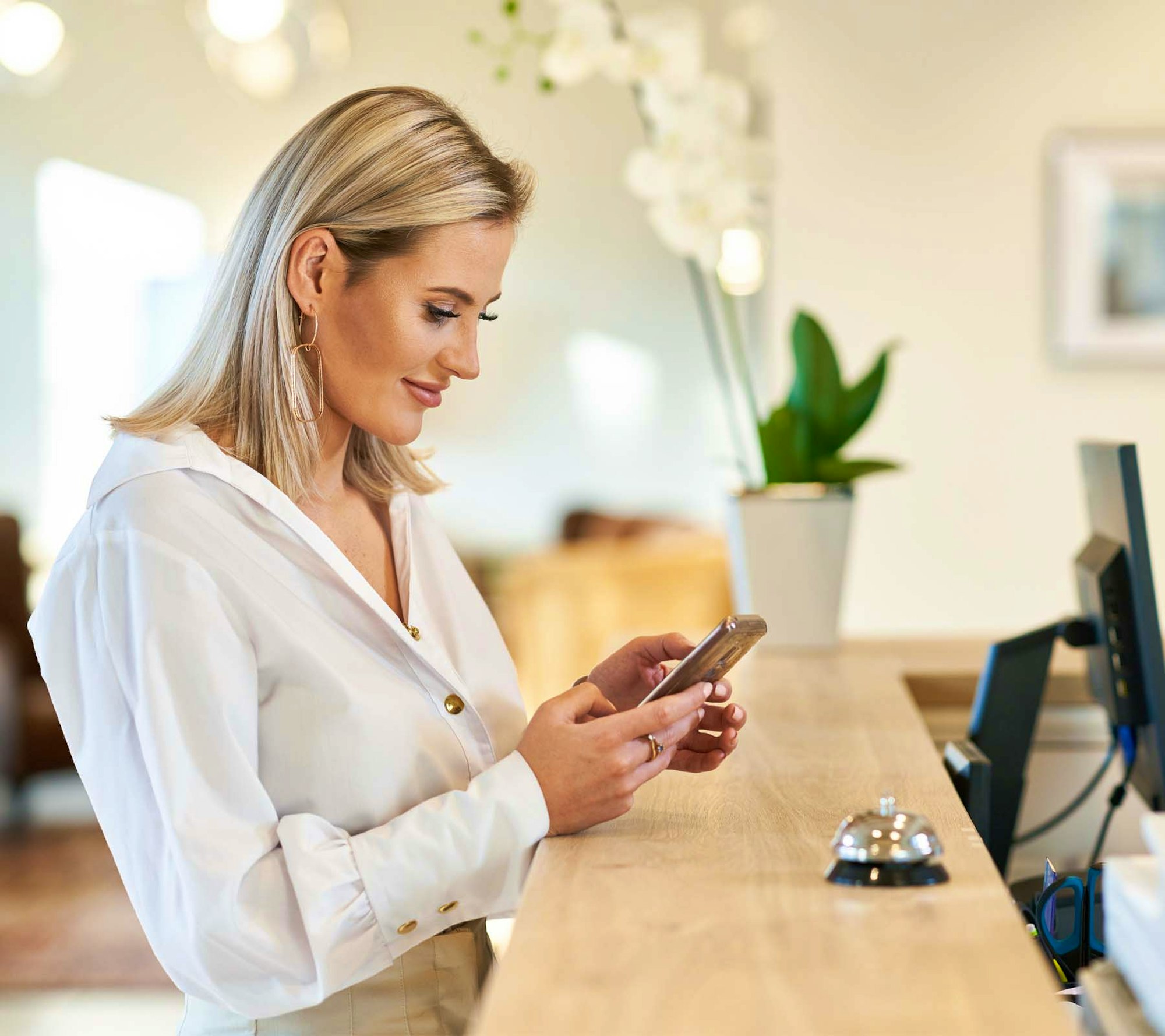 Woman at reception desk on her phone smiling