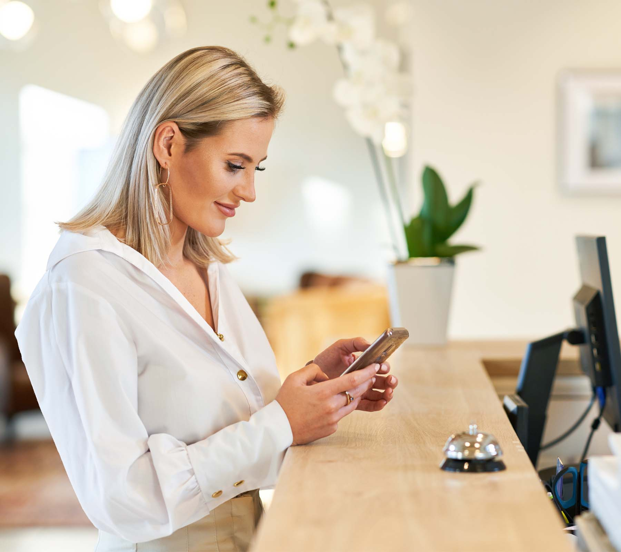 Woman at reception desk on her phone smiling