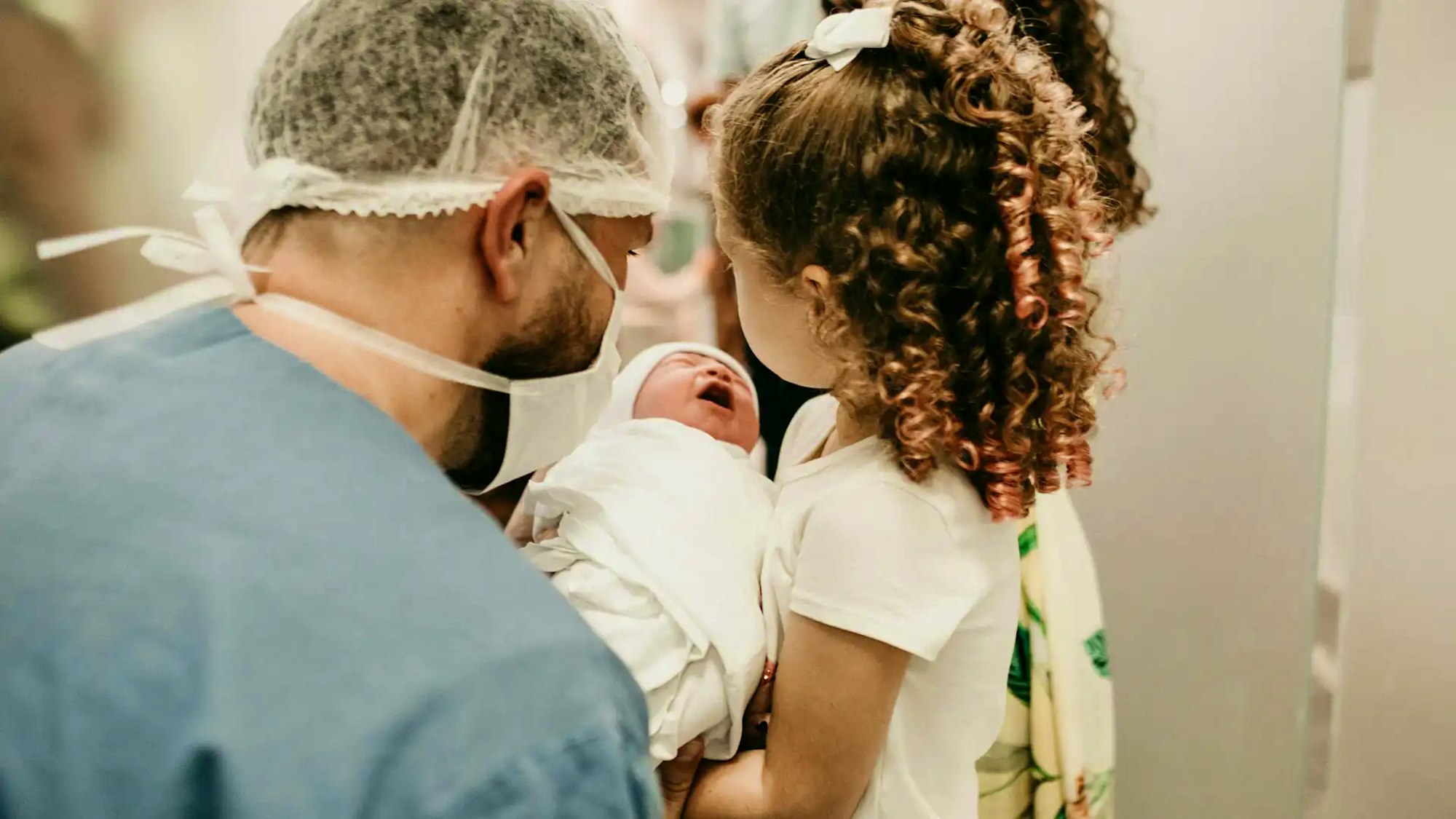 Doctor and young girl looking at newborn baby