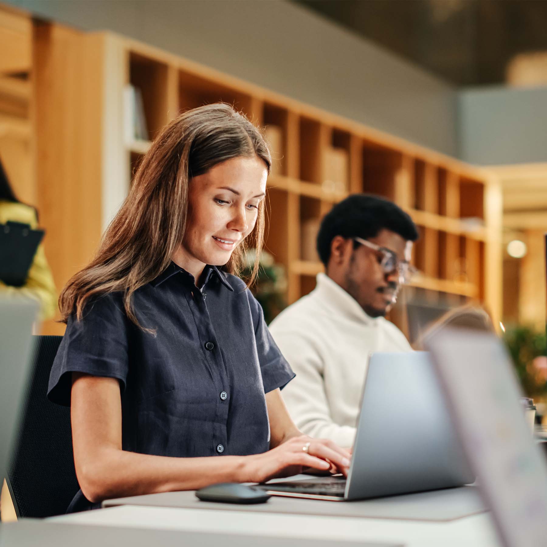 Coworkers working side by side on laptop