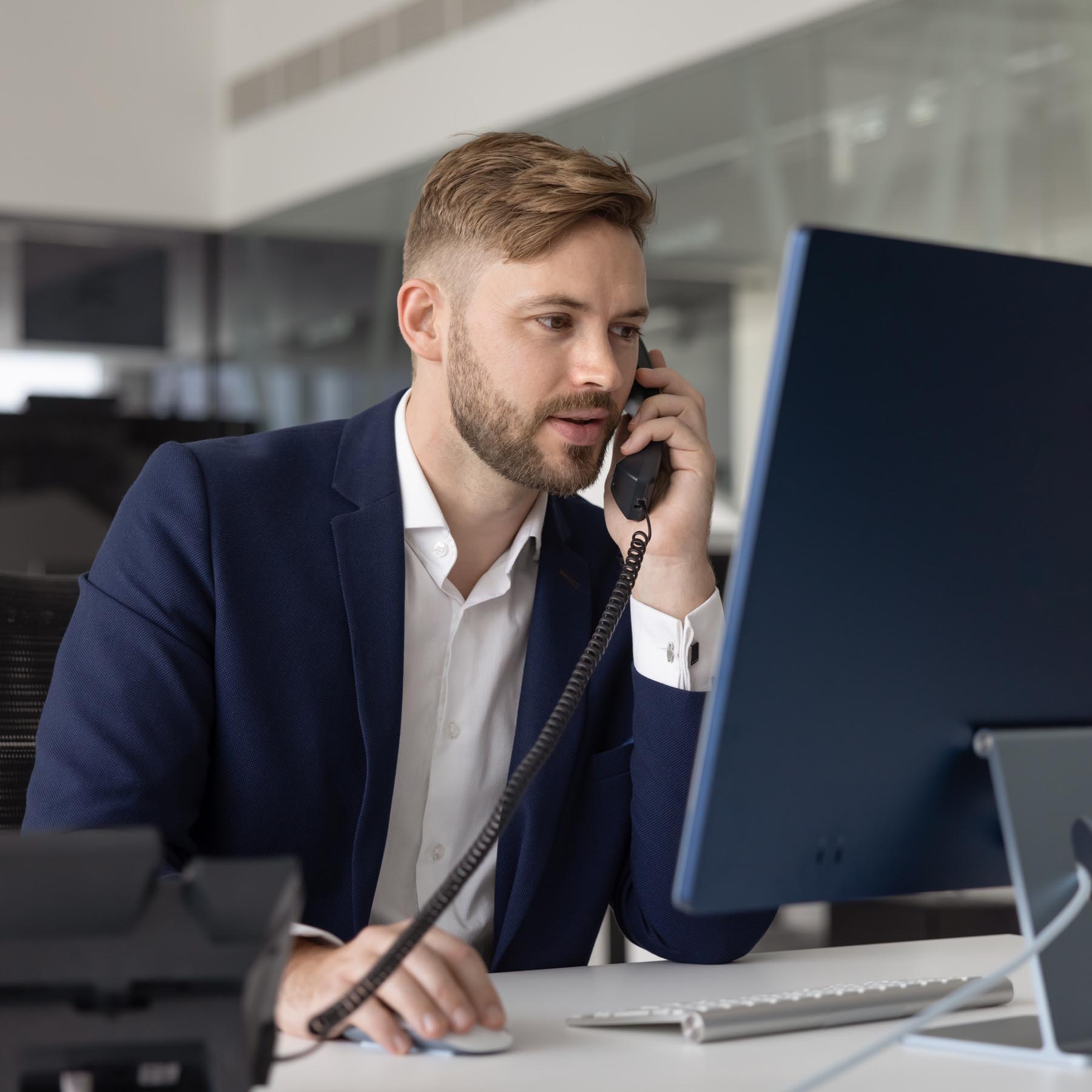 man in navy suit on phone to customer