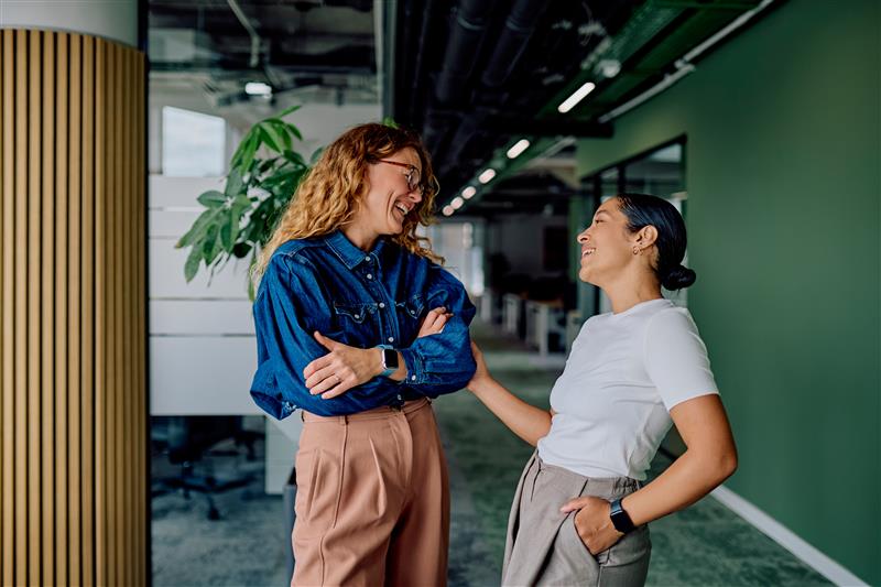 Female co-workers laughing together in hallway