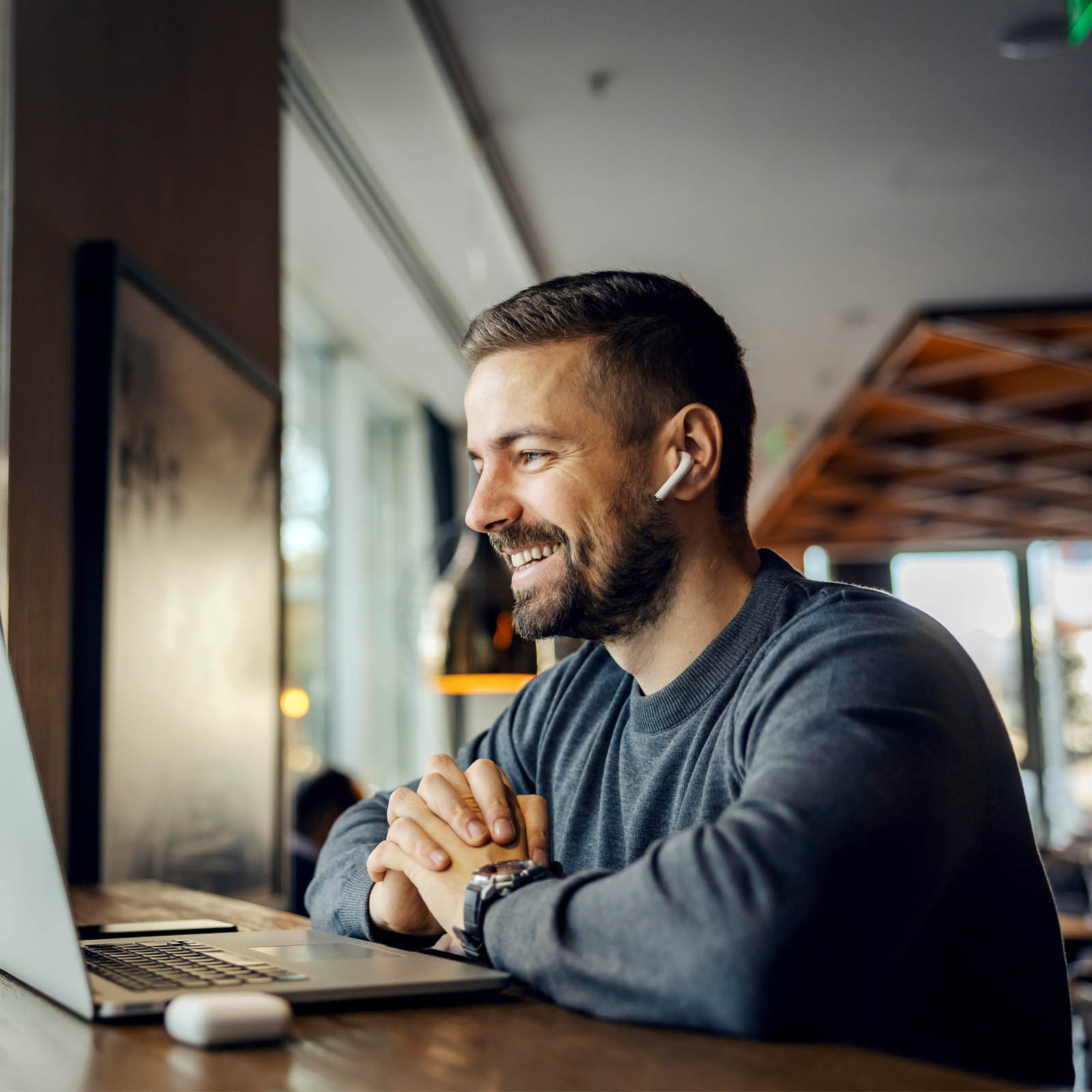 Man with earphones in talking to customer on laptop