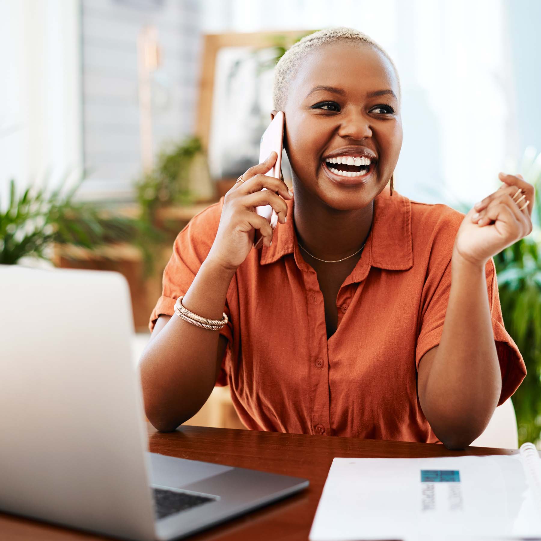 Woman on mobile phone laughing in home office