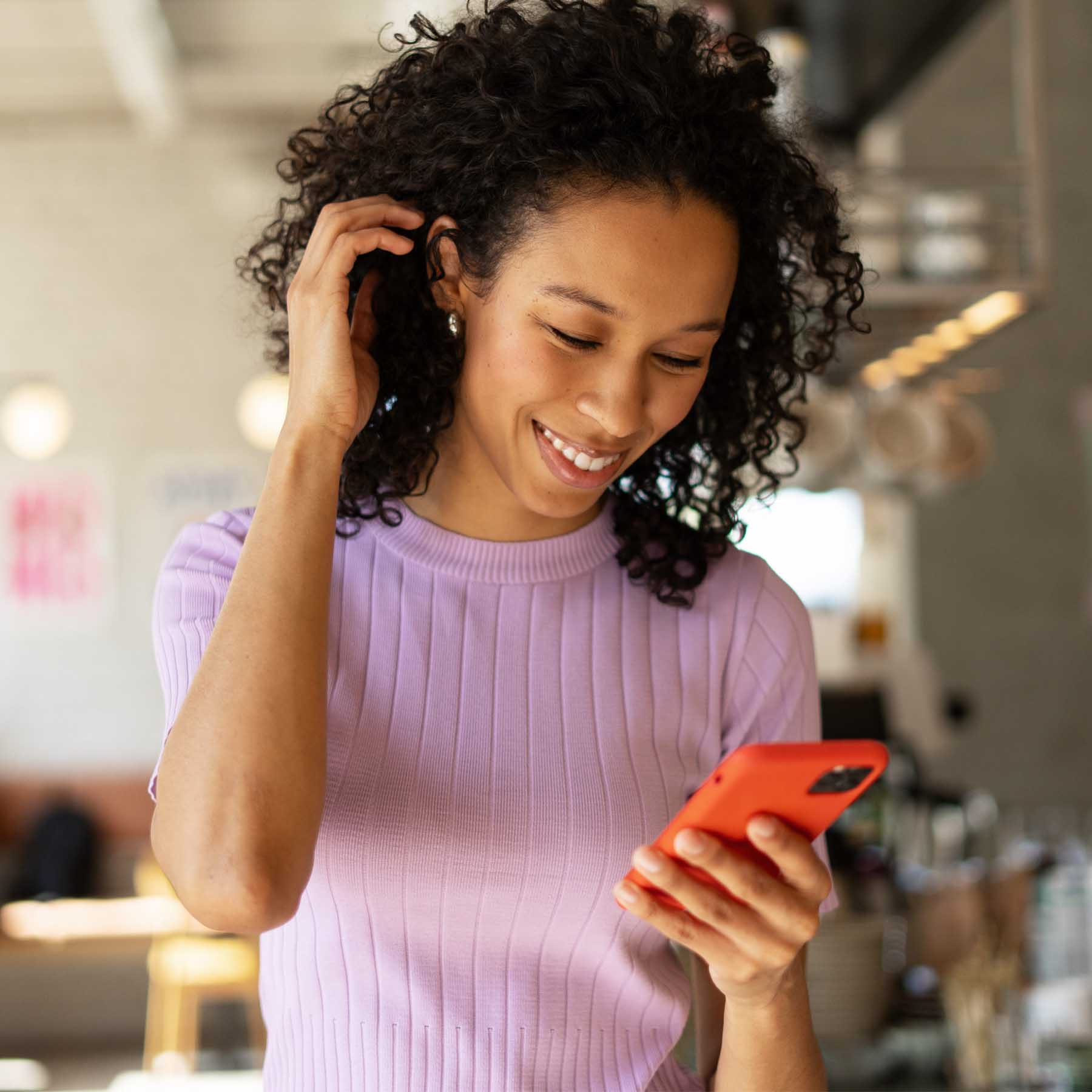 Woman on phone smiling with her hand through hair
