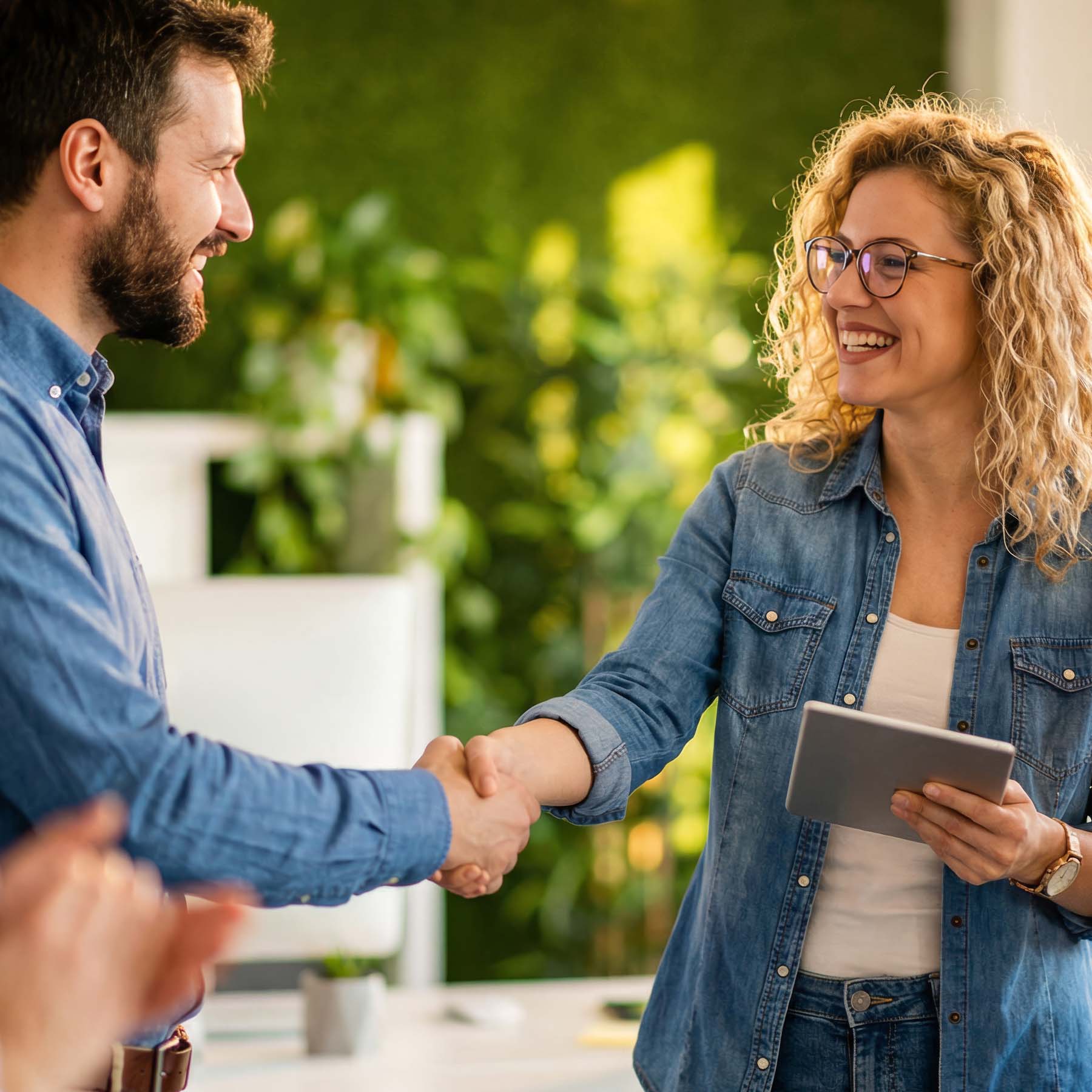Colleagues shaking hands whilst woman holds ipad