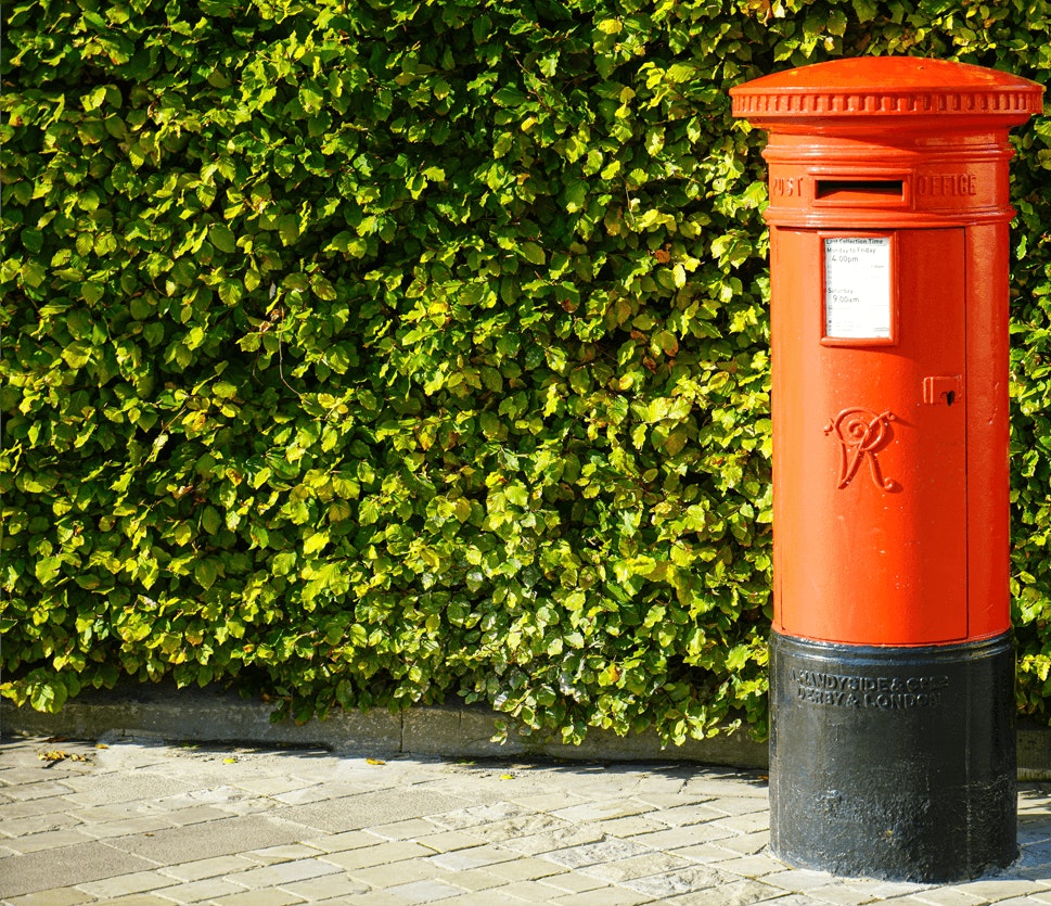 UK Red Letterbox against Green Hedge