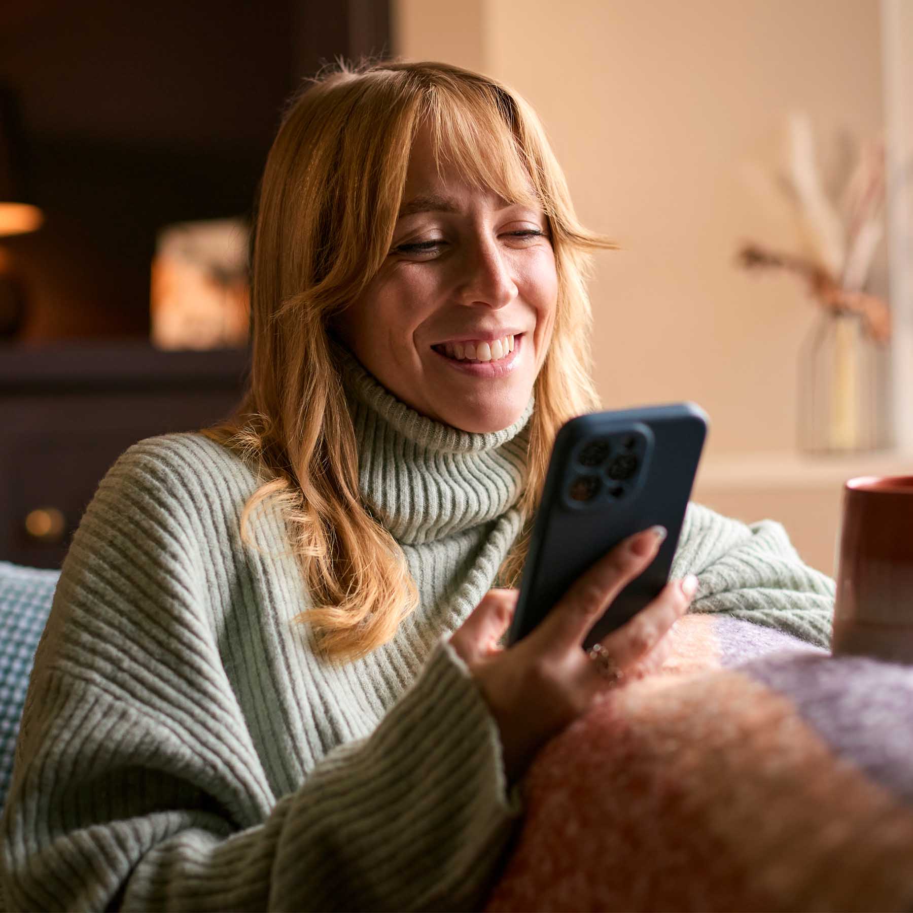 woman on sofa with mobile phone smiling