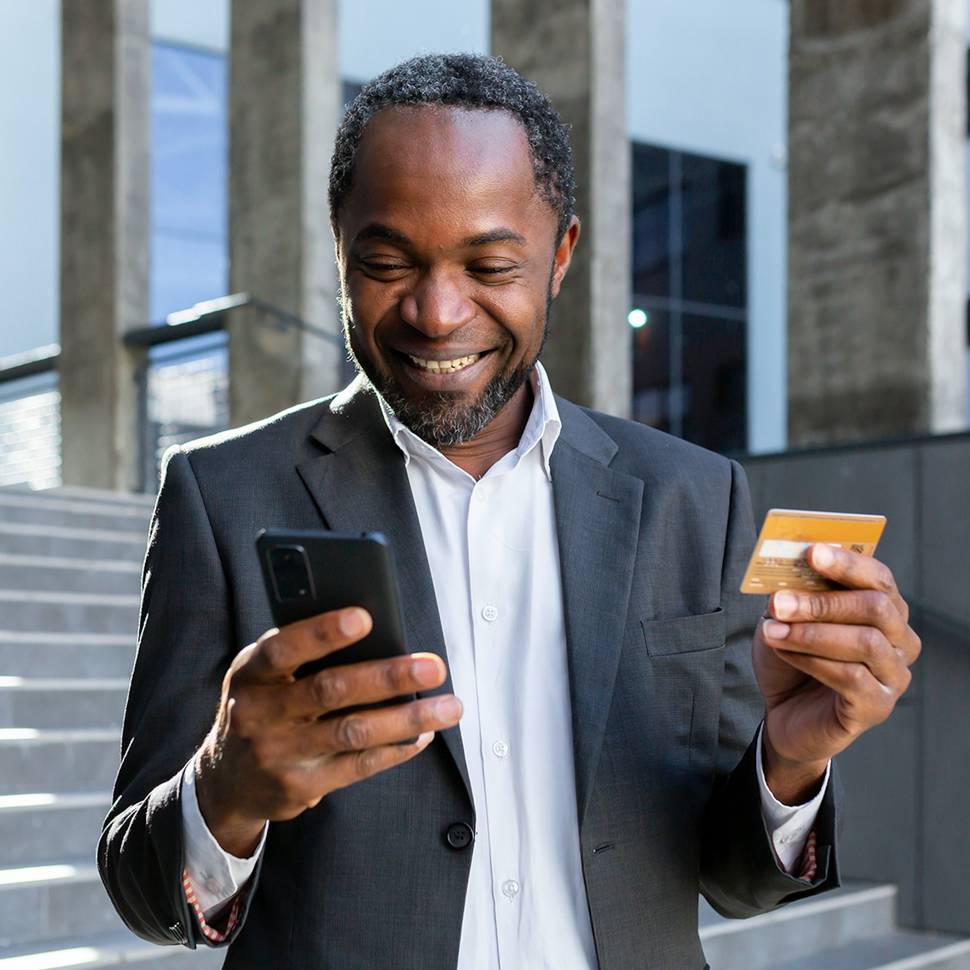 Man with phone and credit card in hand smiling