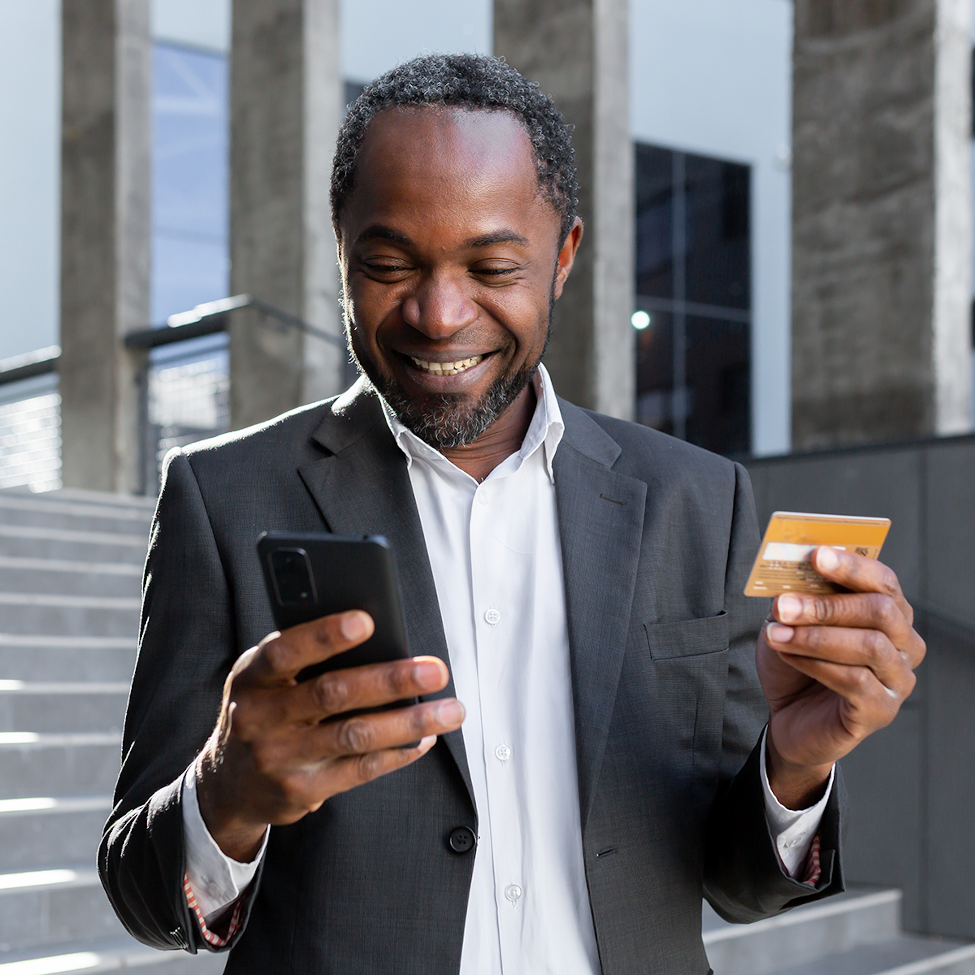 Man with phone and credit card in hand smiling