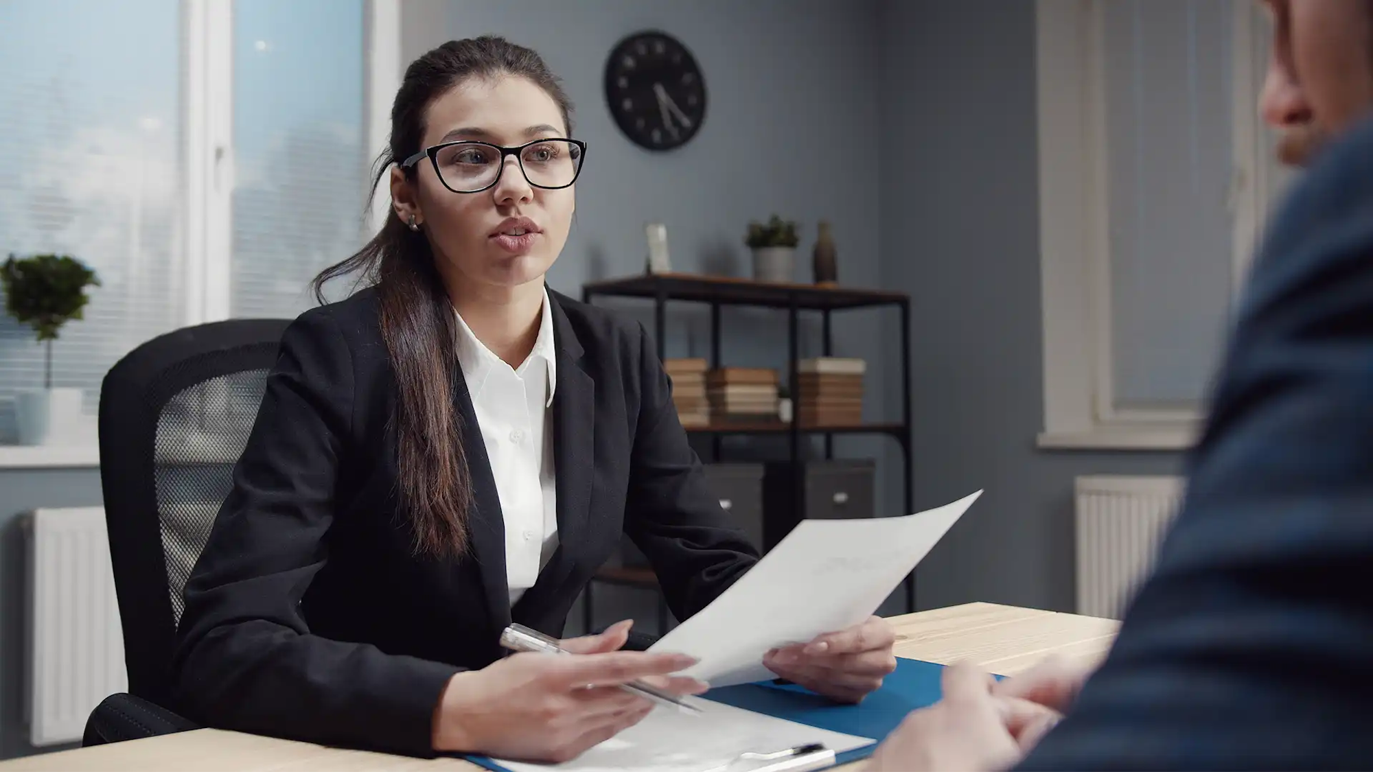 Female recruiter with glasses looking over male candidate CV