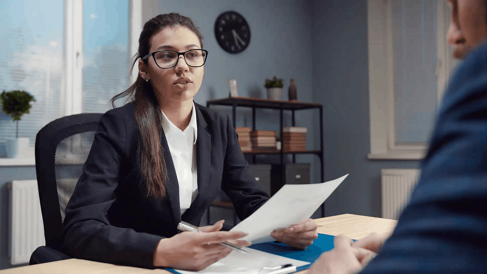 Female recruiter with glasses looking over male candidate CV