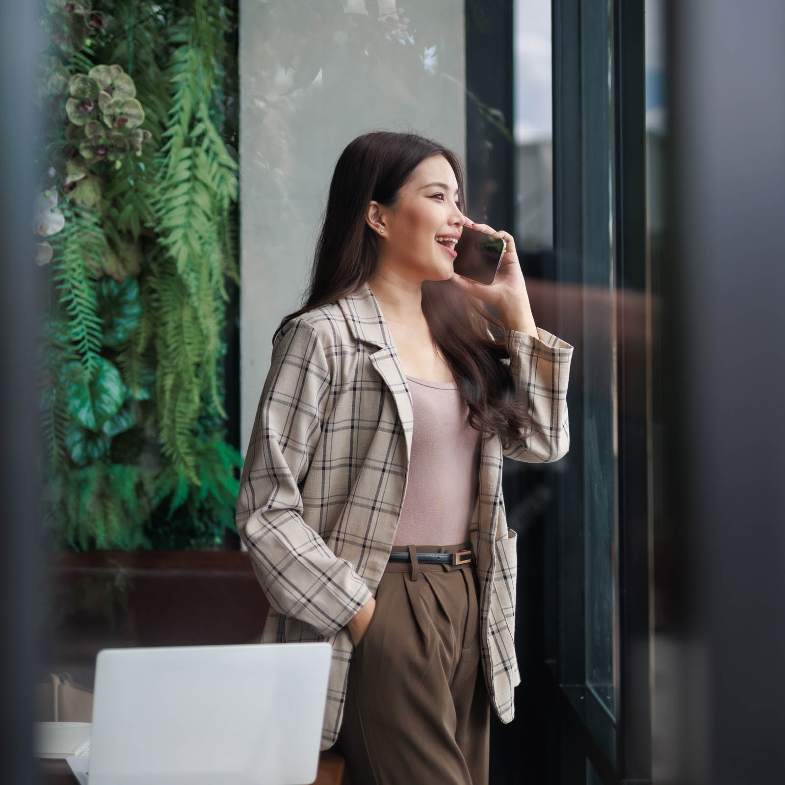 Woman on phone looking outside window laughing